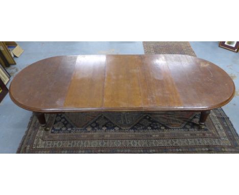 Late 19th century oak extending dining table with three extra leaves, fluted legs with brass caps and castors, 