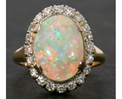 Opal and diamond cluster ring, the oval shaped cabochon opal 14 x 10mm approx, surrounded by 20 small diamonds (four small di