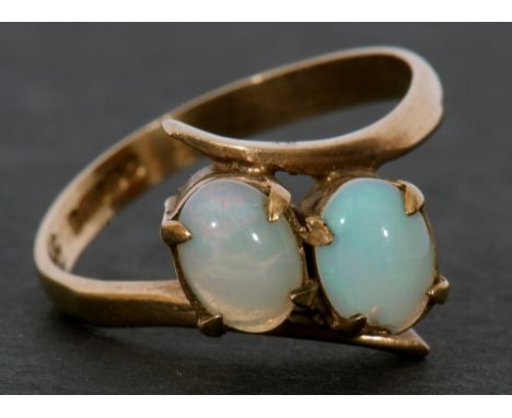 9ct gold and opal cross-over ring featuring two oval cabochon opals raised between plain polished shoulders and shank (one op