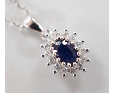 A modern 9ct white gold, sapphire and diamond set oval cluster pendant, overall 15mm,on a modern 9ct white gold chain, 40cm, 