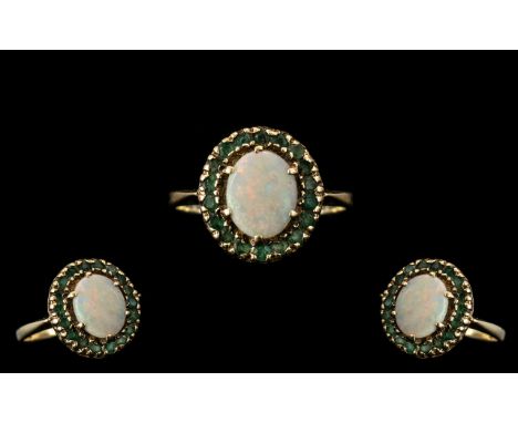 A 9ct Gold Dress Ring Set with Central Opal surrounded by round cut emeralds, fully hallmarked. 