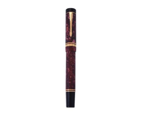 Parker, Duofold Centennial, a red marbled fountain pen, the cap with gilt arrow clip and double cap band, the oblique medium 