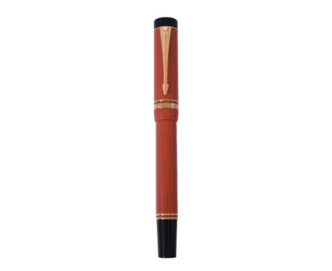Parker, Duofold International, an orange fountain pen, the cap with gilt arrow clip and double cap band, the oblique medium n