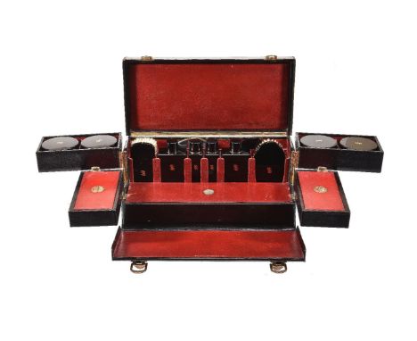 S. T. Dupont, a black leather travelling vanity case, 1930s, with a loop handle and brass clasps, opening to a red leather in