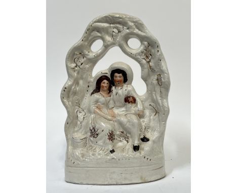 A Staffordshire flatback model of a marriage depicting a man and woman with Spaniel dog under a floral bough, with painted po