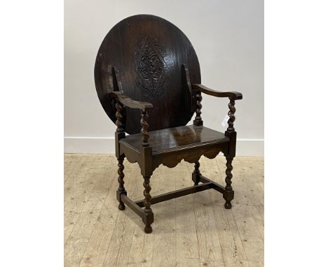 An oak monk's bench of 18th century design, the lozenge carved circular back rest over spiral turned arm rests and supports, 