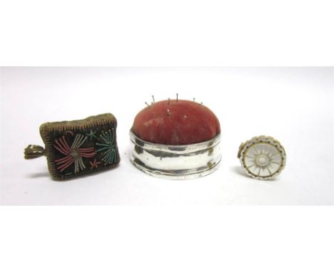 A SILVER TABLE PIN CUSHION  by William Comyns, marks very worn, of circular form 7.7cm diameter; a beaded decorated sack pin 