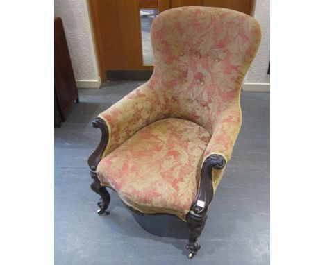 A VICTORIAN BUTTON BACK AND UPHOLSTERED ARMCHAIR with cabriole frontal supports, raised on brass castors