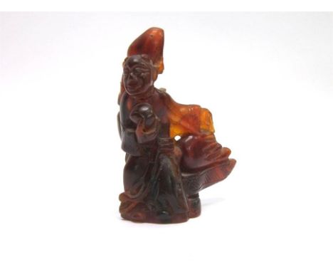 AN AMBER NETSUKE in the form of a man with outstretched left arm, 7cm high (broken and glued).