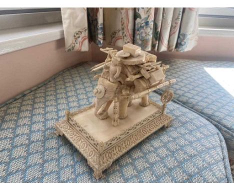 A 19th Century Indian carved ivory elephant group, formed as a travelling tradesman sitting on top of a striding elephant and