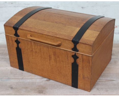 An Arts & Crafts light oak sewing box of domed casket form with black metal strap work and visible dovetail joints, the inter