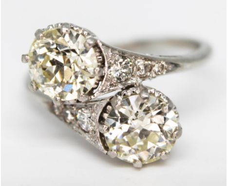 A diamond cross over ring, the two stones weighing approx. 1.12 &amp; 1 carat, diamond set shoulders, platinum band, gross wt