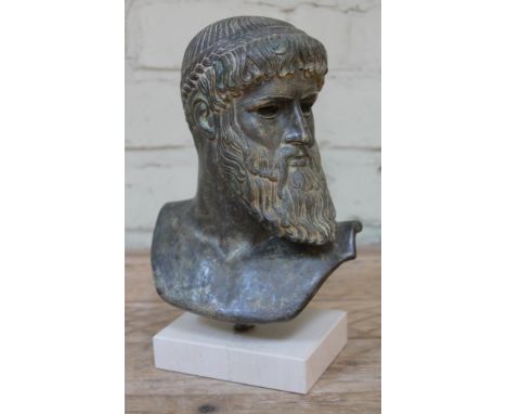 A pottery bust depicting Zeus after the antique with verdi-gris bronze effect finish, suspending above a white marble plinth,