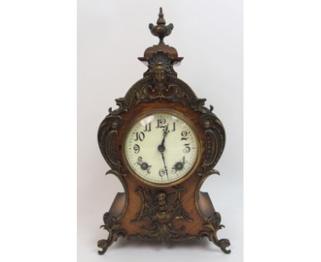 A late 19th century / early 20th century walnut mantle clock with ormolu cherub mounts and urn surmount, with German movement