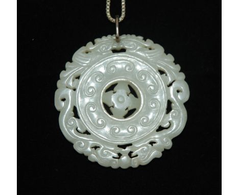 A Chinese jade pierced circular medallion carved with felines surrounding a central articulated boss, with white metal chain,