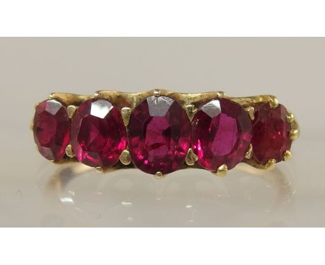 A five stone ruby ring the five graduated rubies are claw set to a scallop shaped mount, finger size N1/2