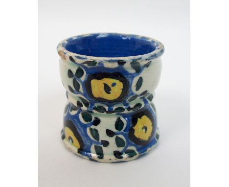 Jessie M King (1875-1949) A pottery egg cup of waisted form, hand painted in blues and yellow with stylised decoration, with 