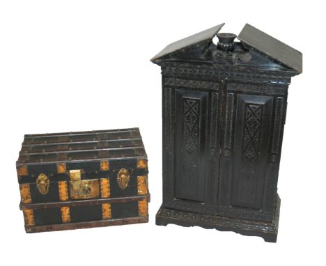 A Victorian ebonised oak miniature cabinet with a pair of carved doors enclosing two short and three long drawers beneath a b