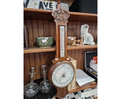 An early 20th century carved oak aneroid barometer. 