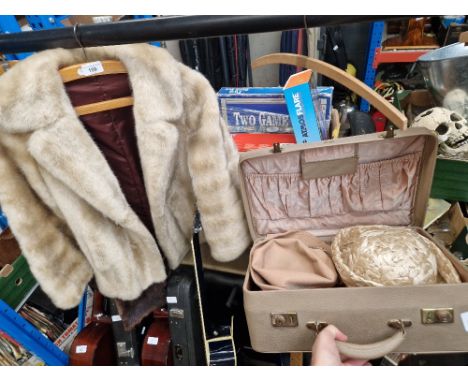 A suitcase with vintage ladies hats and faux fur jacket. 