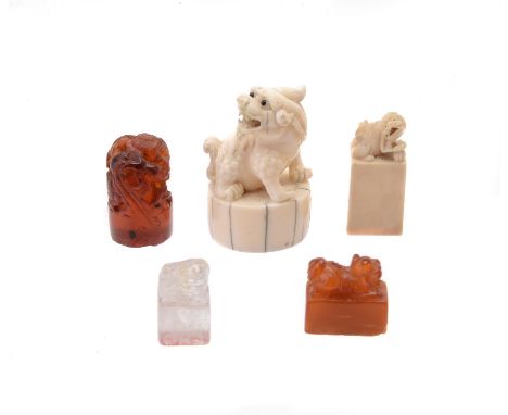 A group of five Chinese seals, including one amber seal surmounted by a Buddhist lion finial, 2.3cm long; one amber seal surm