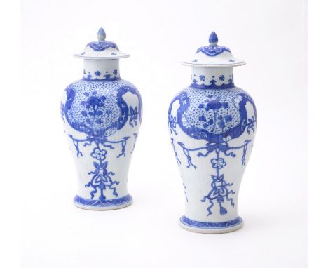 A pair of Chinese 'Shipwreck' blue and white vases and covers, Kangxi, painted with pendant ribbons and foliage, 25.5cm high 