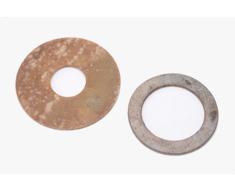 A Chinese mottled brown jade disk, bi, possibly Han dynasty, carved on both sides with a wide band of faceted bosses within n