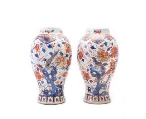 A pair of Chinese Imari slender baluster vases, Kangxi (1662-1722), painted and gilt with exotic birds perched on rockwork in