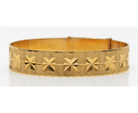 A vintage rolled gold bangle with bright cut decoration, 6cm diameter. 