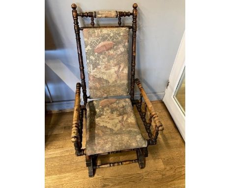 A late 19th century American stained beech rocking chair, the turned frame with spindle arm supports and tapestry padded back