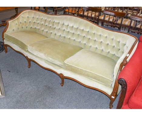 A 20th century carved walnut three-seater sofa, button backed and raised on scroll supports, 218cm by 72cm by 72cm H