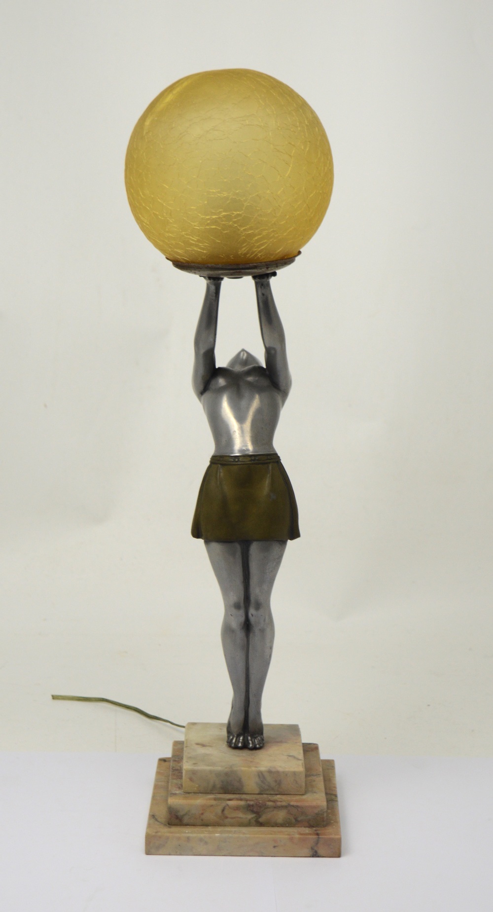 An Art Deco style lamp of a lady holding an ambercoloured globe, on a stepped marble base. CON