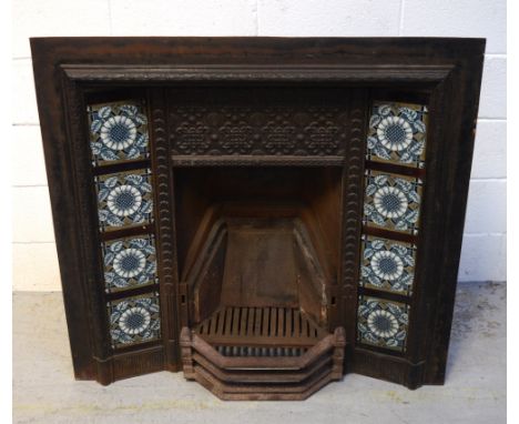 A 19th century cast iron fire insert, decorated in the style of Thomas Jekyll, fireplace flanked by two columns of four ceram