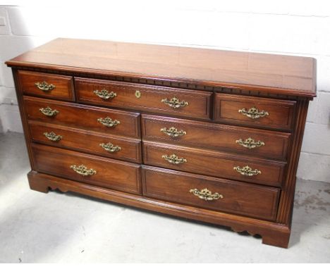 A reproduction long chest of drawers, one central long drawer and two small drawers to either side over six drawers, on plint