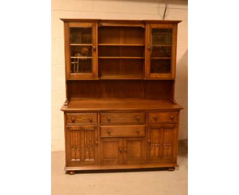 An Ercol dresser with shelves and glazed door above a base with arrangement of drawers and doors, width 155cm.