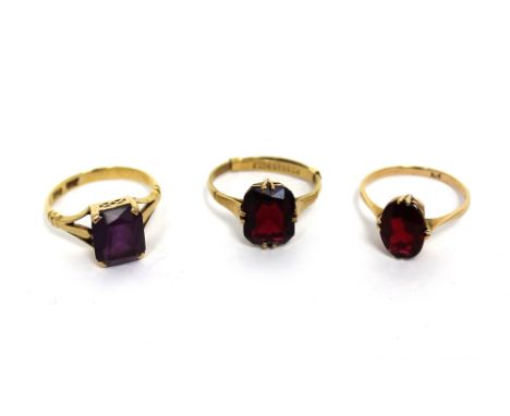 Three 9ct yellow gold dress rings; two set with red coloured stones and one with purple stone, sizes K, L and M respectively,