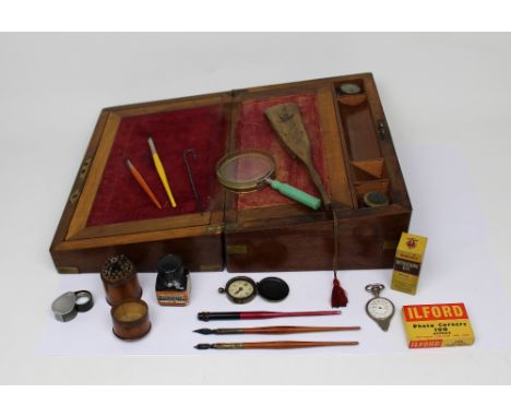 An early 20th century walnut writing box with brass corners, containing a wooden Italian tourist fan, large magnifying glass,