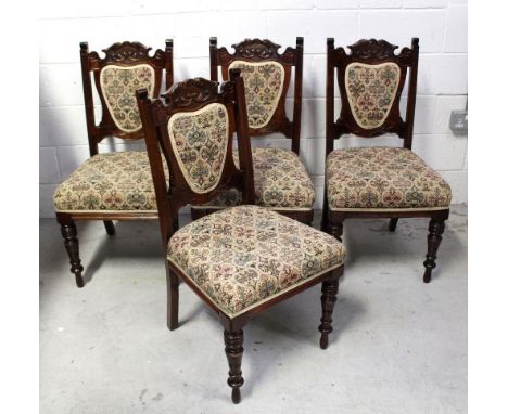 Four early 20th century mahogany shield-back dining chairs, carved top rail over tapestry shield-back and seat to turned supp