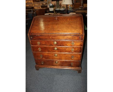 An 18th century oak bureau with fall enclosing fitted drawers, pigeon holes (a/f) and well, above four graduated drawers, on 