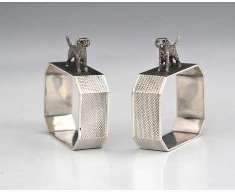 A pair of Art Deco style silver novelty napkin rings, each with a cast and applied figure of a standing dog or terrier, decor