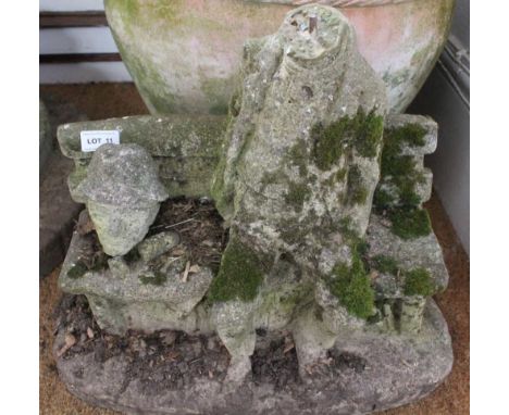A CAST CONCRETE GARDEN FIGURE OF A MAN ON A BENCH 