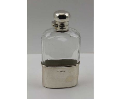 AN EDWARDIAN SILVER MOUNTED FACET CUT GLASS HIP FLASK, the hinged twist cover dated London 1907, the removable cup base, Lond