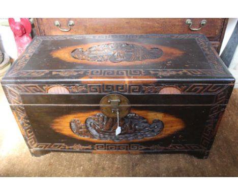AN EARLY 20TH CENTURY EASTERN CARVED CAMPHOR WOOD CHEST, the hinged cover carved with a panel of courtly figures in a garden,
