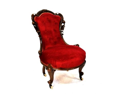 A Victorian stained walnut nursing chair upholstered in red button-back velvet, on cabriole legs and castors.