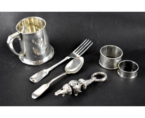 A small group of hallmarked silver items to include a Christening mug, two napkin rings, a spoon and fork from a child's chri