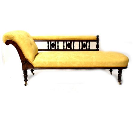 An Edwardian mahogany chaise longue with button-back upholstery in a cream fabric, with pierced back rail, on turned legs wit