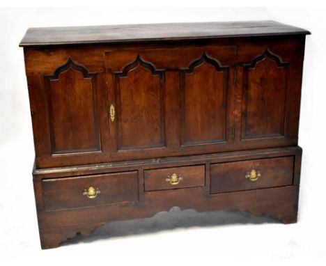 A Georgian oak Lancashire chest with single door over three drawers, carved Gothic-style panels to the front, on stylised bra