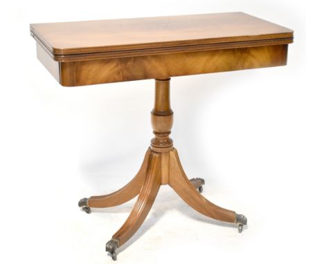 A 19th century style mahogany fold-over card table on a turned column with four outswept legs to metal lion paw feet and cast