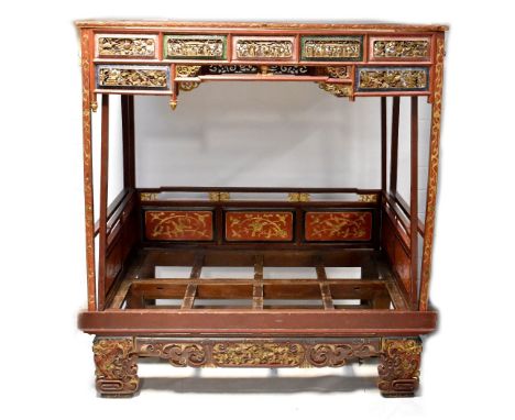 An impressive Chinese carved and gilded wedding bed, the canopy with a profusely carved frieze depicting peonies, figures in 