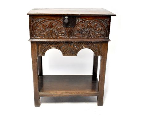 An antique carved oak Bible box with iron fittings and carved sunflower front panel, on a later stand with undertier, 83 x 68